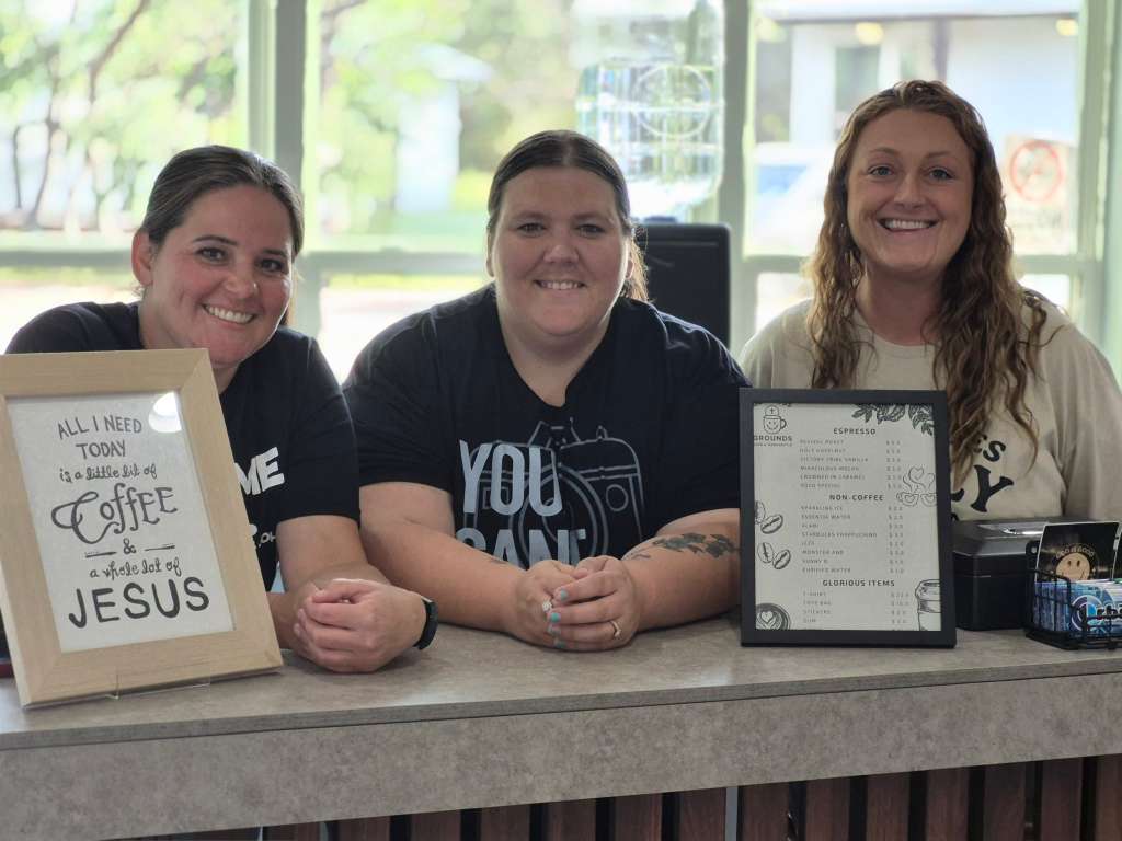 Three smiling volunteers at Glorious Grounds Cafe